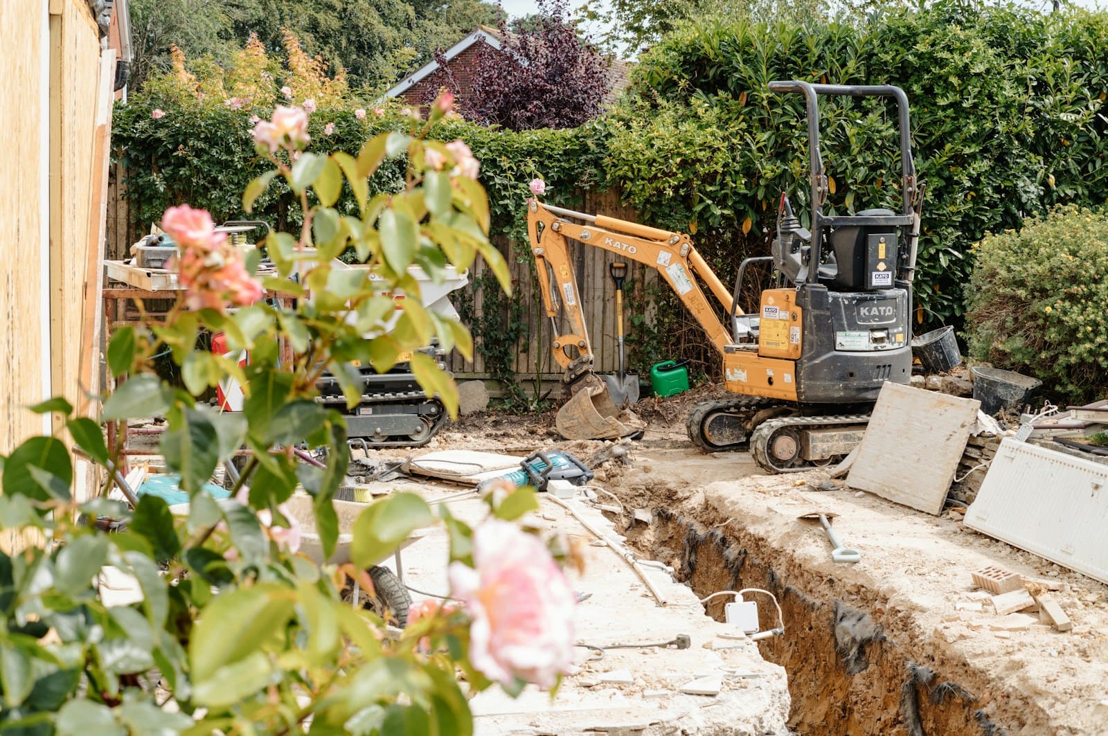 A mini digger beside a trench in a garden